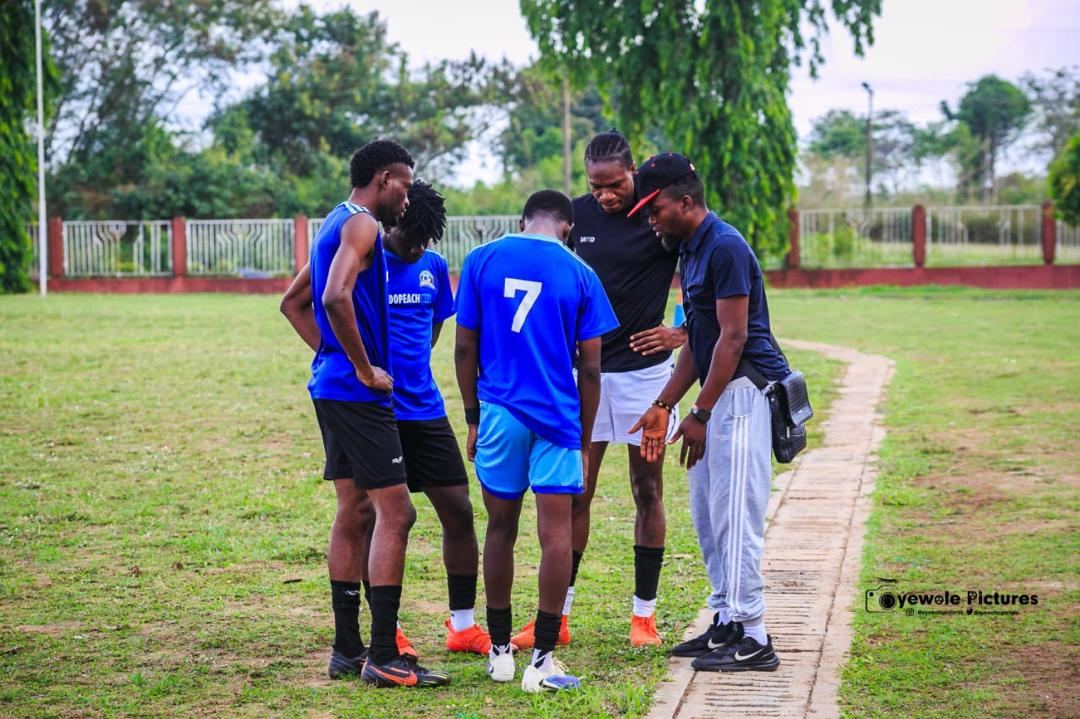 Coach and players in a team huddle on the pitch