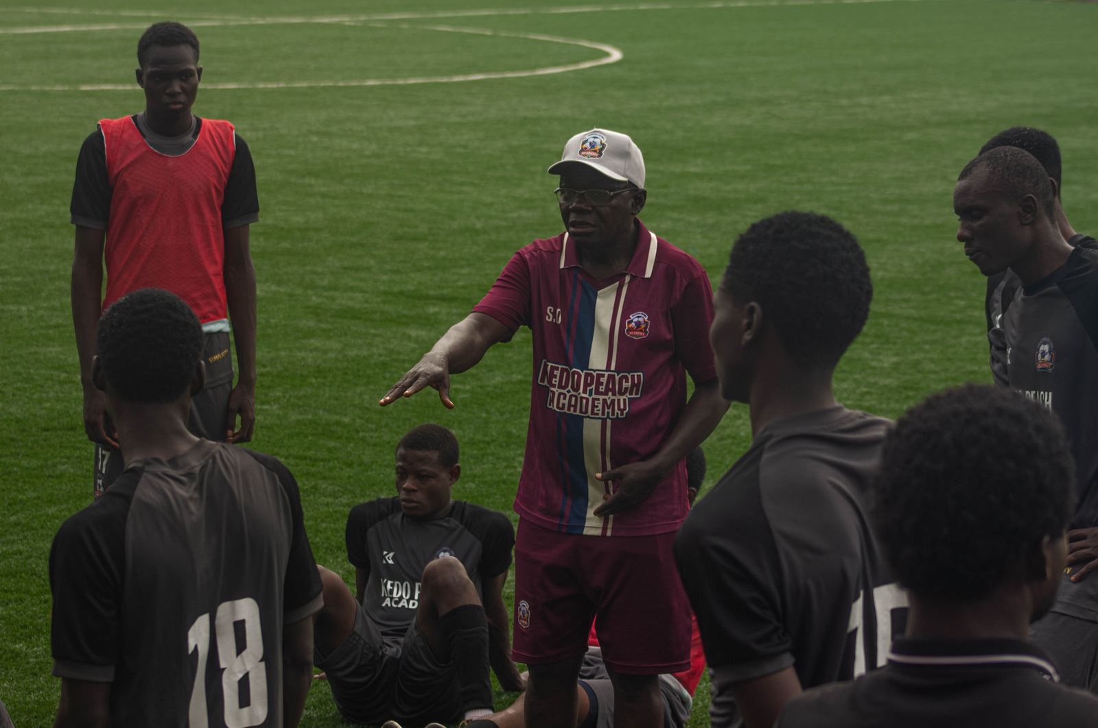 Coach addressing seated KEDOPEACH players