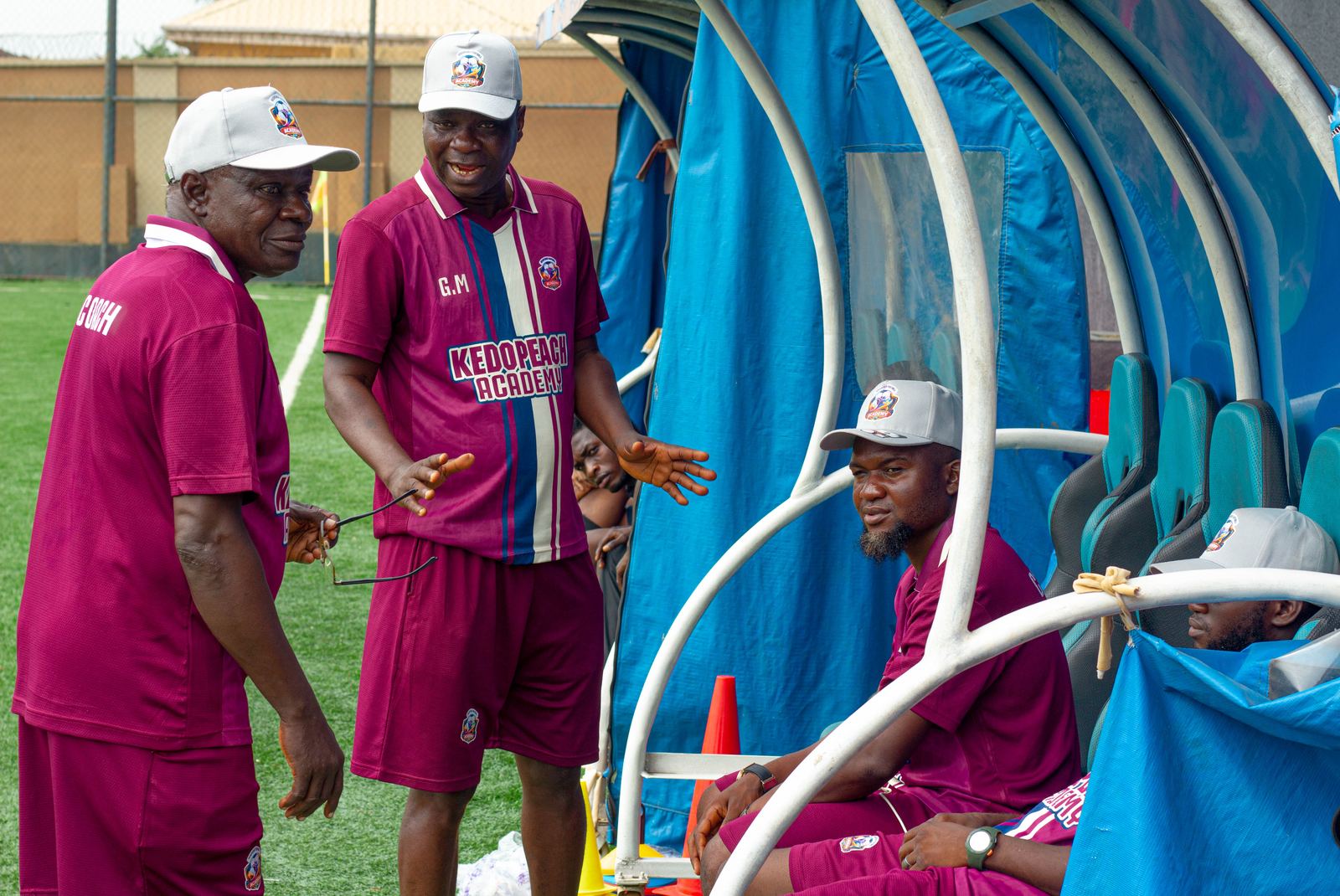 KEDOPEACH Academy coaches in discussion by the dugout