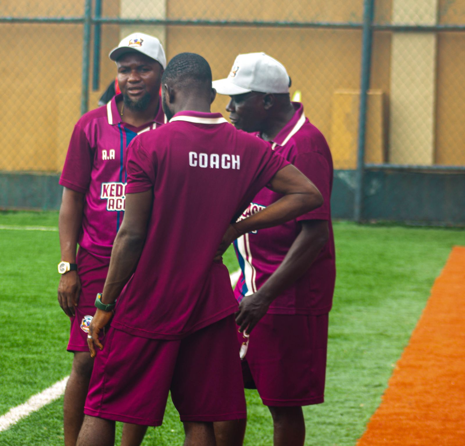 KEDOPEACH Academy coaches in a pitchside huddle