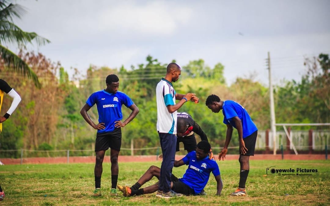 Teammates and staff assisting a KEDOPEACH player on the pitch